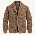 A brown cable-knit cardigan sweater with a shawl collar and dark brown buttons, shown on a clean off-white background.