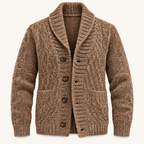 A brown cable-knit cardigan sweater with a shawl collar and dark brown buttons, shown on a clean off-white background.