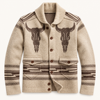 A men's knit cardigan sweater in a warm beige color, featuring a dark brown western-style design with two large bull skull motifs on the chest, striped patterns on the sleeves and hem, and brown buttons.